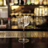 Empty Bach Retro Fizz Cocktail Glasses standing on a dark bar surface with blurred bottles on the background