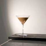 Crescendo Martini Glass filled with Espresso Martini cocktail standing on a dark wooden surface and a white background