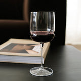 Wine glass with red wine on a dark surface next to a book