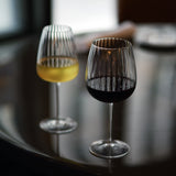Gin & Tonic Jenever Gin glass filled with red wine standing on a dark surface, blurred white wine glass filled with white wine in the background