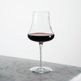 Tentazioni Bordeaux Red Wine Glass filled with red wine standing on a light marble surface and a white background
