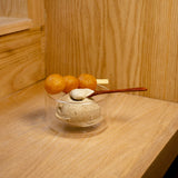 Thermic Sublime double-wall dessert bowl filled with sesame ice-cream with a wooden spoon inside and deep fried dough balls on a skewer standing on a wooden surface and background