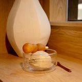 Thermic Sublime double-wall dessert bowl filled with sesame ice-cream and deep fried dough balls on a skewer standing on a wooden surface and a white vase in the background