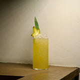 Top Class Highball Glasses with a yellow cocktail garnished with a slice of star fruit standing on a wooden surface with a ivory wall in the background