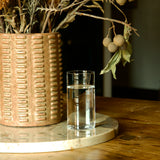 Top Class Highball Glass filled with water standing on a marble round surface and a vase with dry flowers in the background
