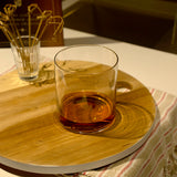 Top Class DOF glass filled with whisky, standing on a wooden tray with décor in the background