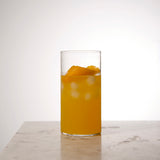 Top Class Highball Glass filled with an orange cocktail and garnished with a orange twist standing on a light marble surface and light neutral background