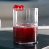 Top Class All Purpose glass filled with red cocktail and garnished with three cherries standing on a dark surface and a blurred background