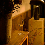 Vinoteque Fragrante wine glass filled with white wine and standing on a wooden table, wooden wall and a table lamp the background