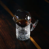 Vinoteque Cognac Glass filled with Cognac laying down in an angle on a DOF glass with warm water on a dark wooden surface