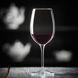 Vinoteque Riserva Red Wine Glass filled with red wine standing on a wooden surface and a black background