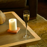 Vinoteque Flute glass filled with sparkling wine standing on a wooden table decorate with a candle