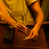 Hands holding Vinoteque Perlage flute filled with sparkling wine on a wooden surface in the background