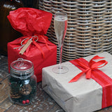 Vinoteque Flute Glass filled with sparkling wine standing on a wrapped Christmas gift next to another gift and a jar with Christmas decorations
