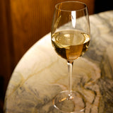 Vinoteque Fragrante glass filled with white wine and standing on a marble surface.