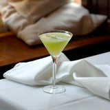 Green cocktail in a martini glass on a white napkin with a blurred background