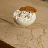 Glass of creamy dessert with a cookie on top on a marble surface