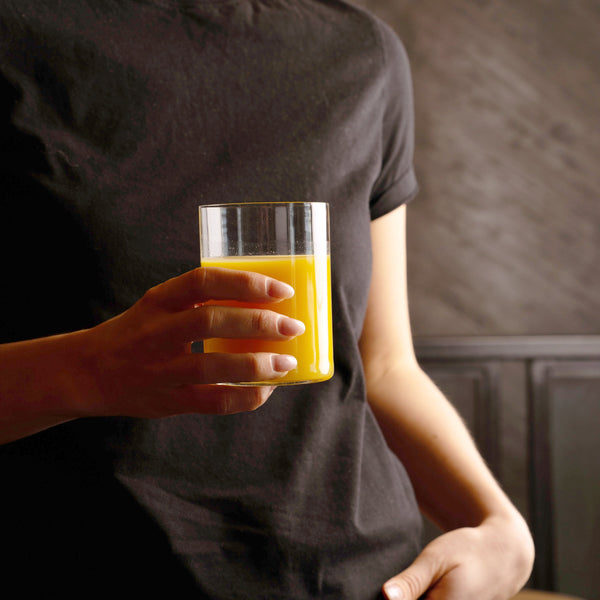 Top Class glass with orange beverage held in hand on a black background 