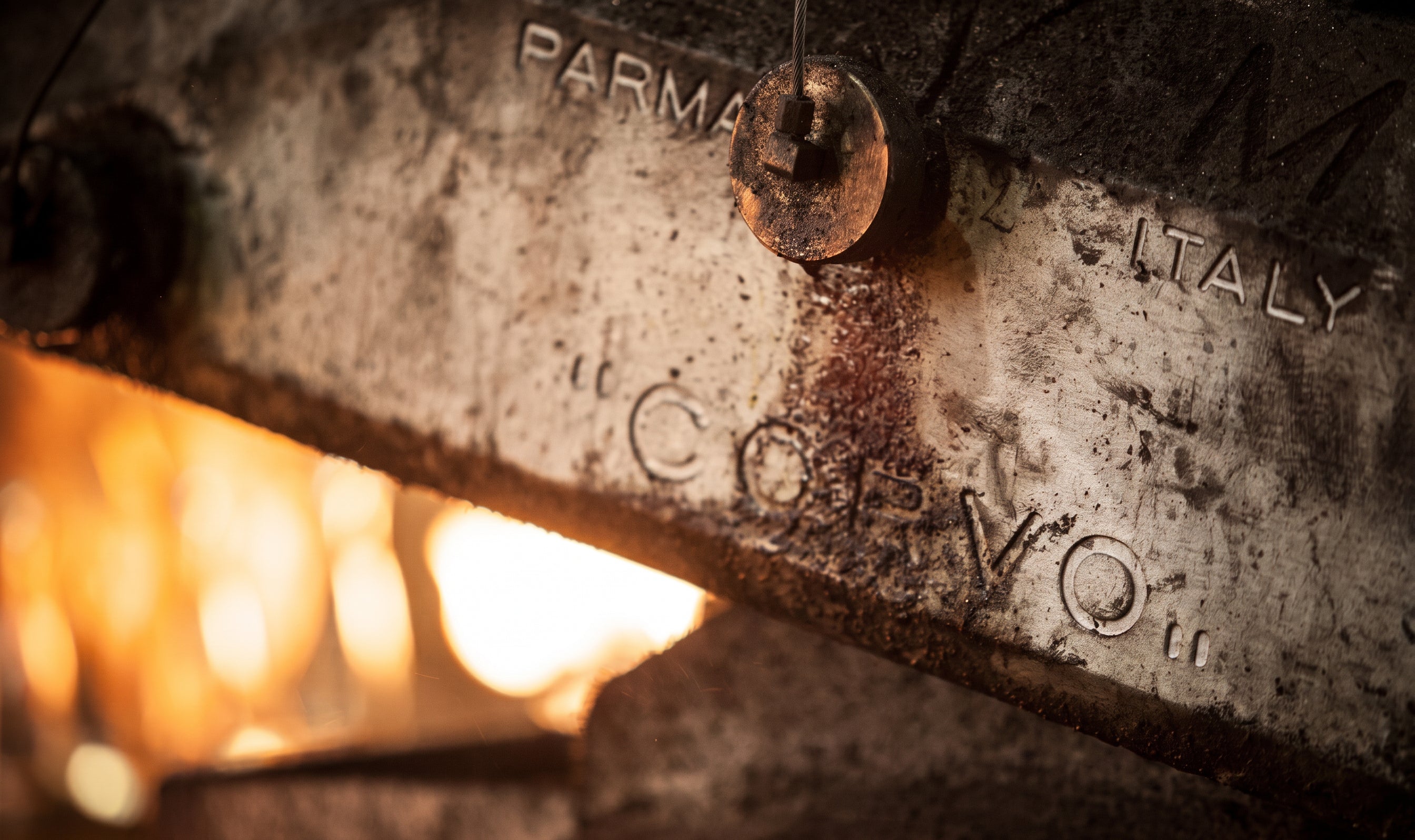 Close-up of a metal object with 'Parma Italy' engraved, glowing background