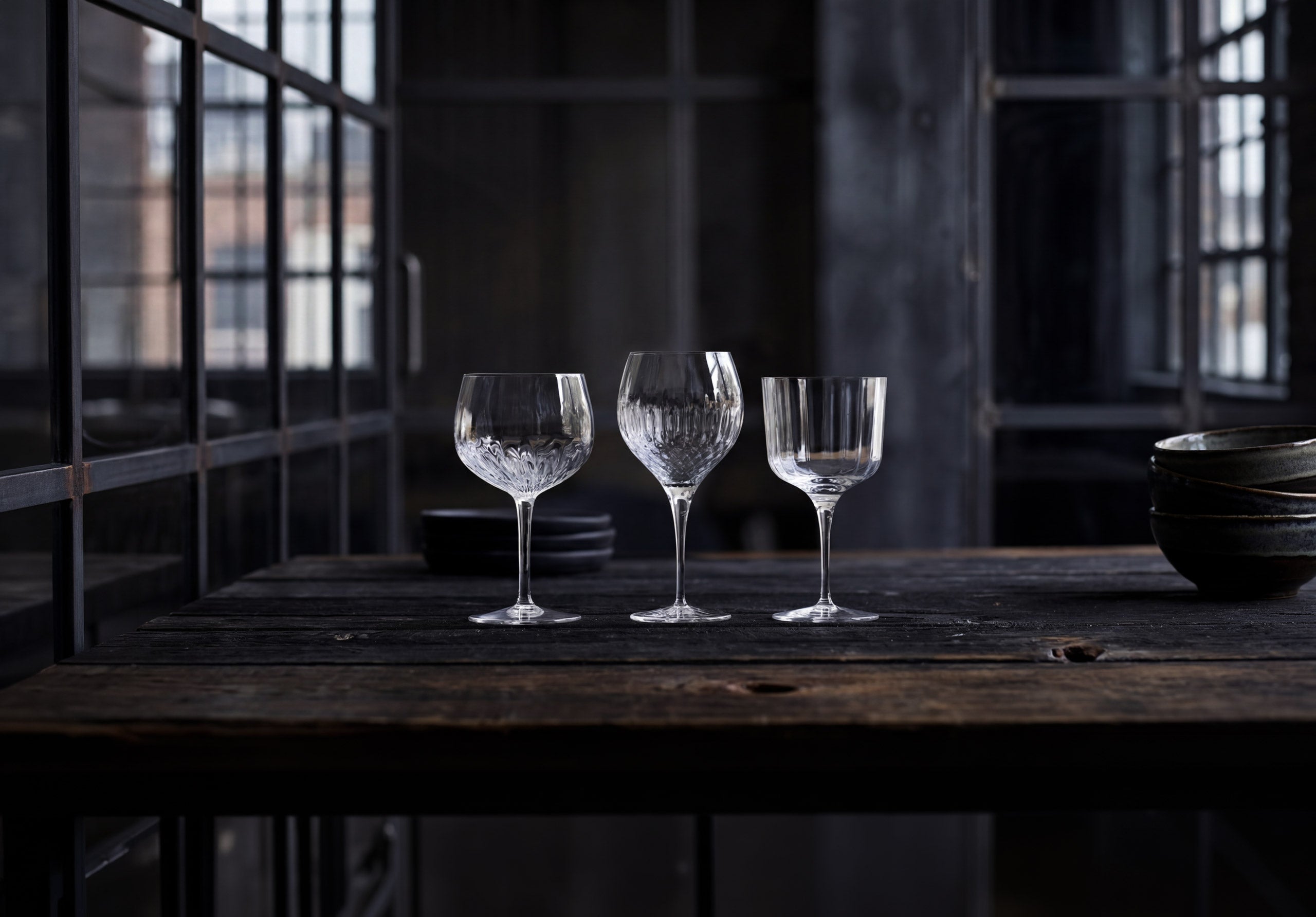 Three crystal glasses on a wooden table with a dark background