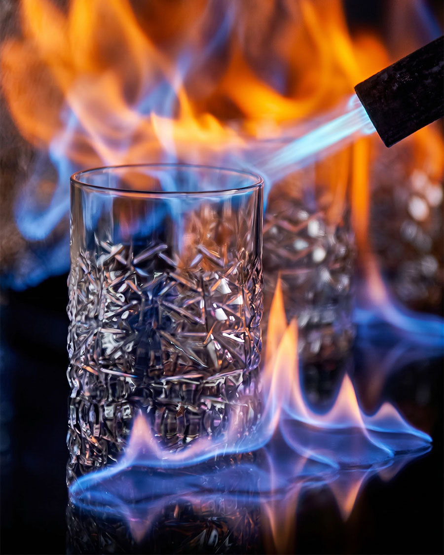 Glass being heated over a flame with a blurred background