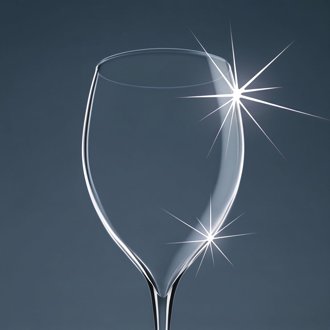 Clear wine glass with light flares on a dark background