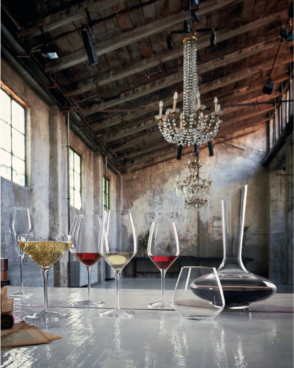 Wine glasses with red and white wine on a table in an elegant room with a chandelier.