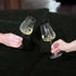 Two hand holding Talismano Chardonnay wine glasses filled with white wine one a dark green background