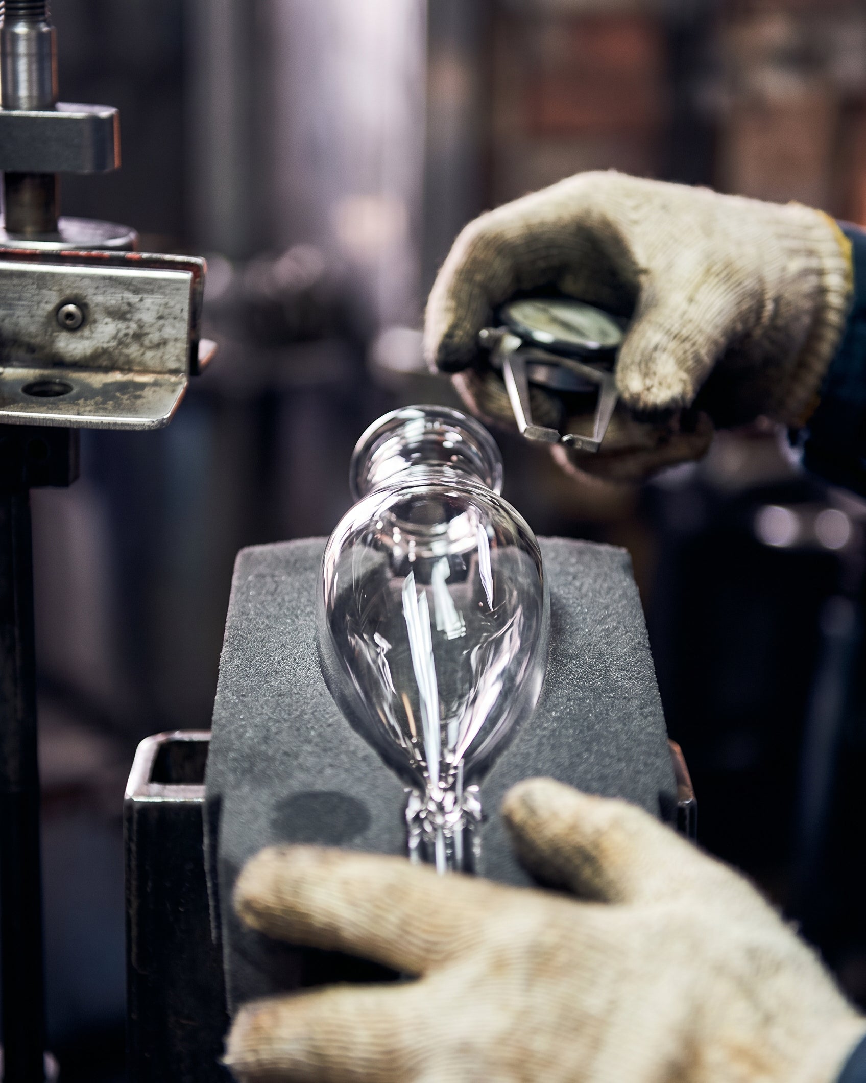 Person wearing gloves holding a glass bulb in a workshop setting