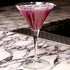 Bach Martini glass with a deep purple cocktail garnished with lavender standing on a black and white marble surface