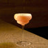 Backdoor '20s Italian Premium Nick & Nora Cocktail glass filled with a pink cocktail and garnished with line zest standing on a marble surface and a dark background