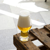 Glass of beer on a wooden pallet with a blurred outdoor background