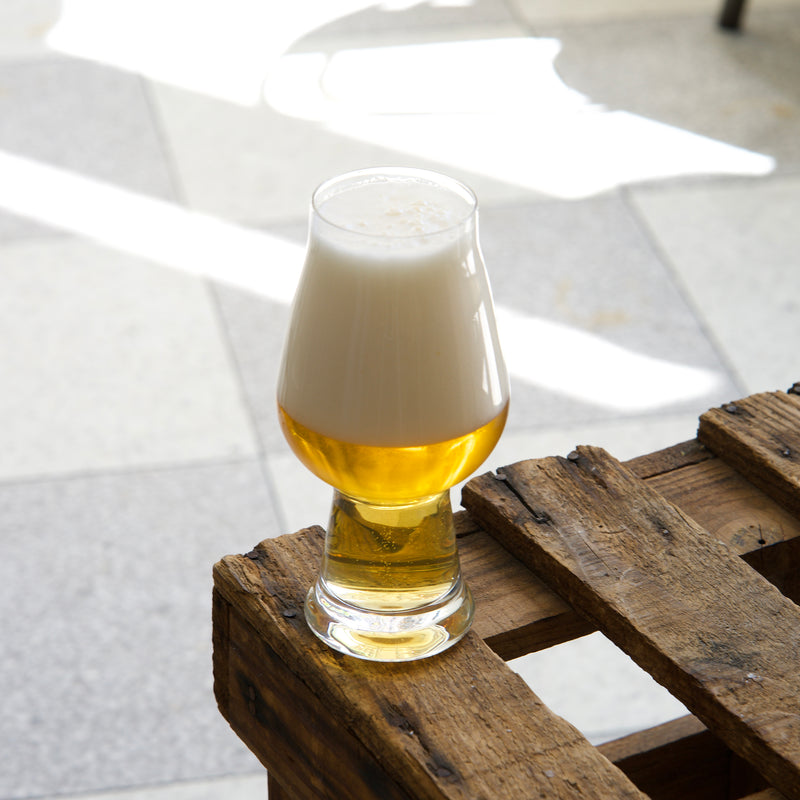 Glass of beer on a wooden pallet with a blurred outdoor background