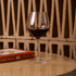 Wine glass with red wine on a wooden table next to a book titled 'Edible Flowers'.