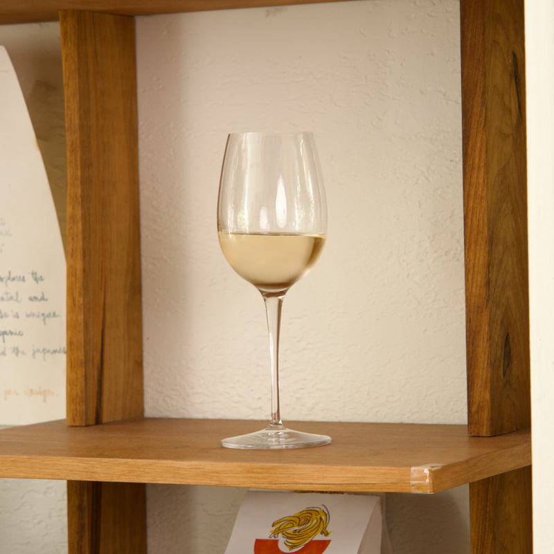 Glass of white wine on a wooden shelf with a neutral background