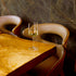 Grandioso Riesling glass filled with white wine standing on a wooden restaurant table with leather chairs in the background and a dark wall