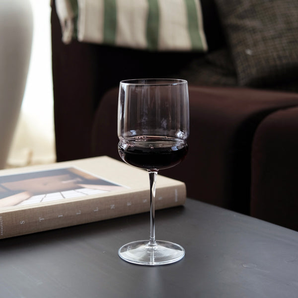 Clear wine glass with red wine on a table with a blurred background