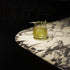 Mixology Cocktail Club DOF glass filled with a bright green cocktail and garnished with a cucumber standing on a marble surface
