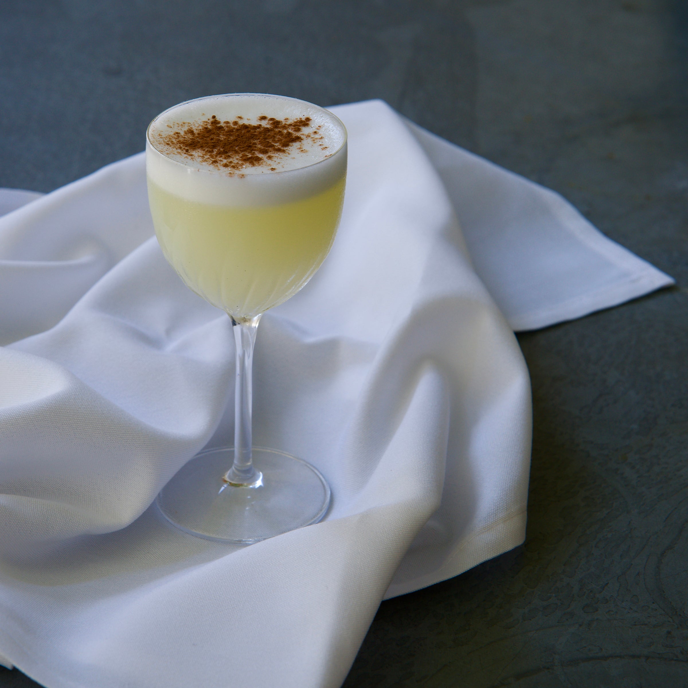 Cocktail with foam and cinnamon on a white cloth