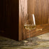 Optica Chardonnay glass filled with white wine standing on a marble surface with a wooden wall background