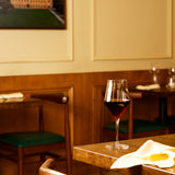 Supremo Bordeaux wine glass on a table filled with red wine in a cozy restaurant setting
