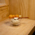 Thermic Sublime double-wall dessert bowl filled with sesame ice-cream with a wooden spoon inside and deep fried dough balls on a skewer standing on a wooden surface and background