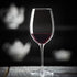 Vinoteque Riserva Red Wine Glass filled with red wine standing on a wooden surface and a black background