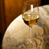 Vinoteque Fragrante glass filled with white wine and standing on a marble surface.