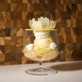 Delicate dessert in a glass dish with floral elements against a wooden background
