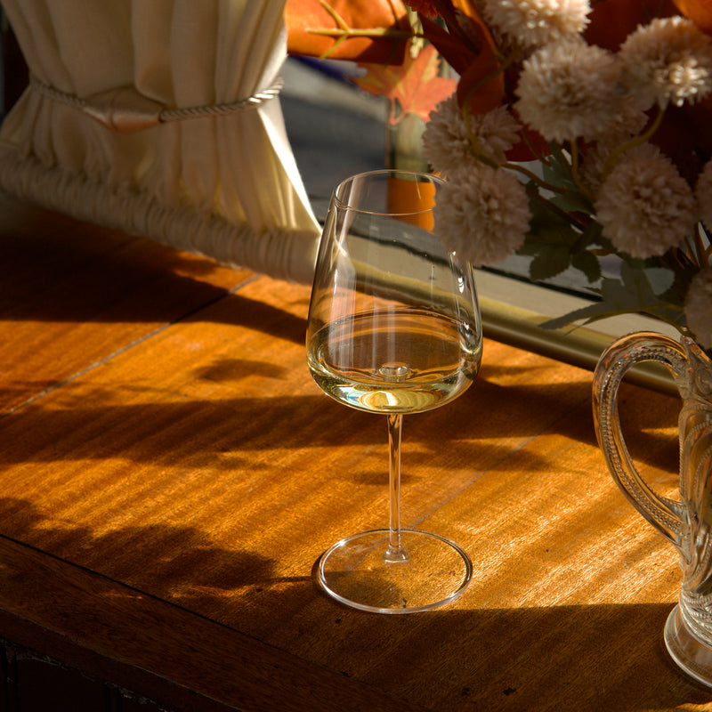 Wine glass with white wine on a wooden table with autumn decorations