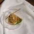 Dessert in a glass bowl with a stick on a white fabric background