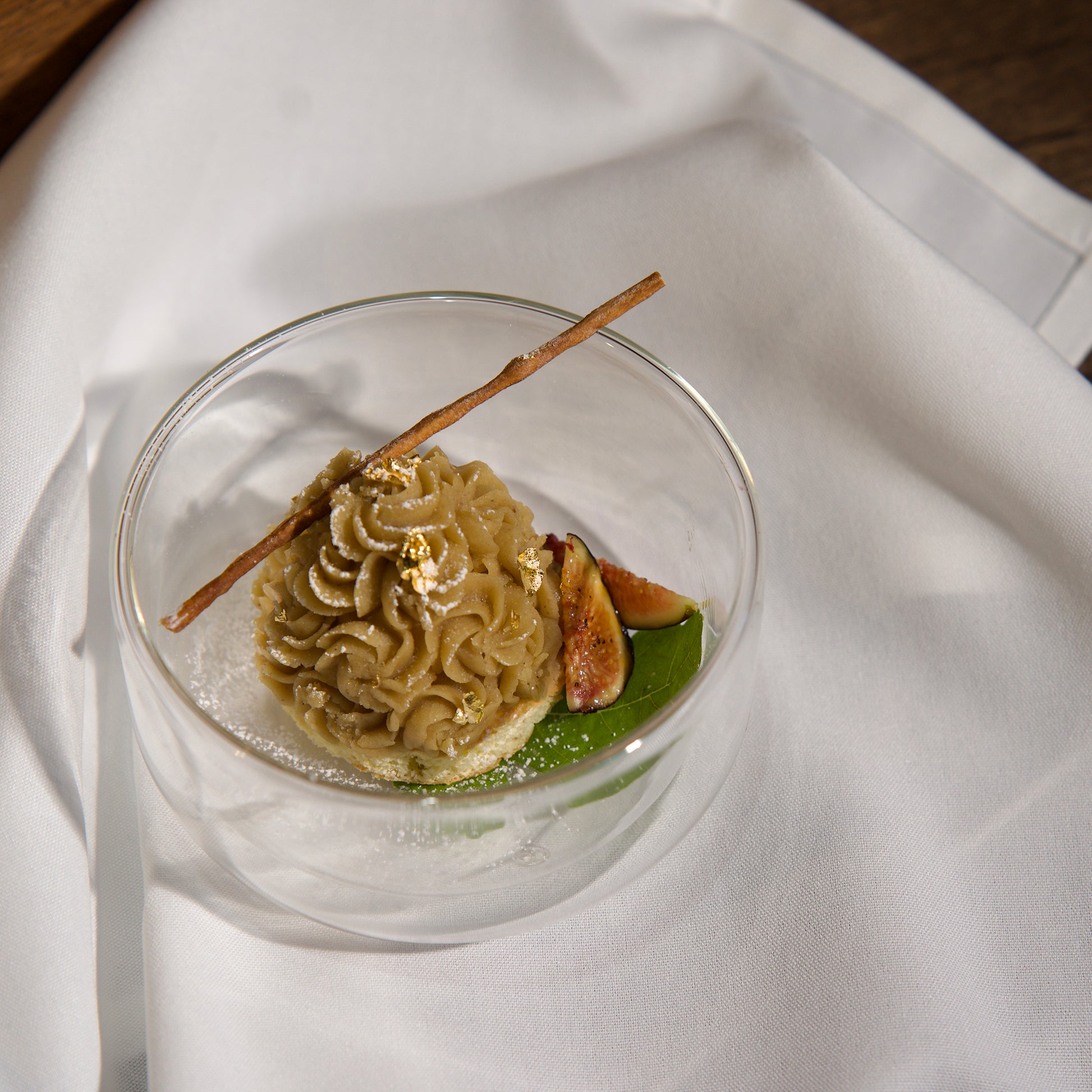 Dessert in a glass bowl with a stick on a white fabric background