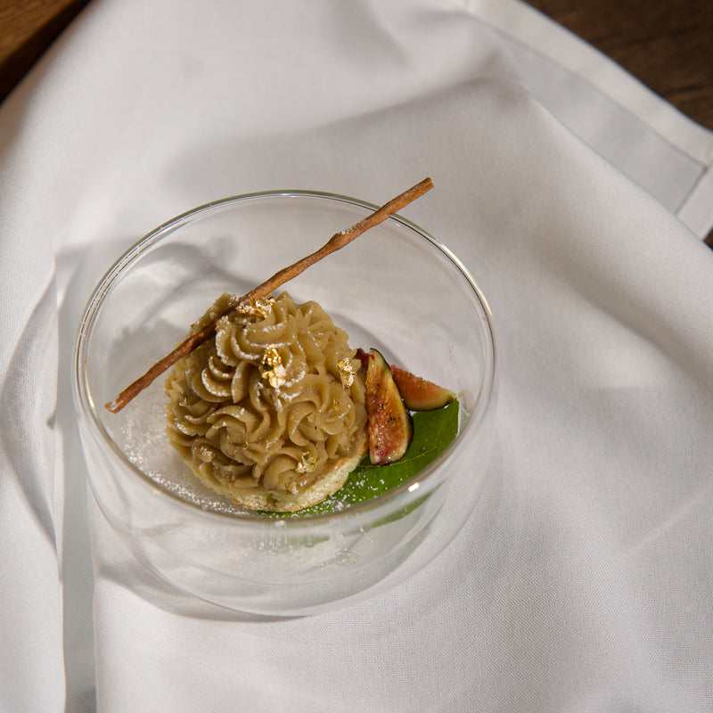 Dessert in a glass bowl with a stick on a white fabric background